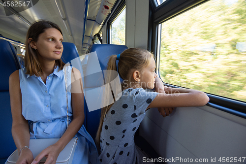 Image of Mom and daughter in an electric train car, look out the window with enthusiasm
