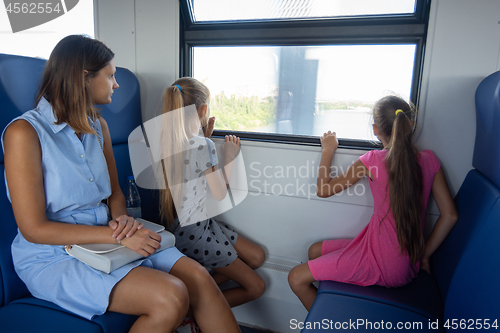 Image of Mom and two daughters ride in an electric train, children look out the window