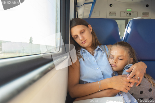 Image of Mom and daughter hugging sleeping in a train car