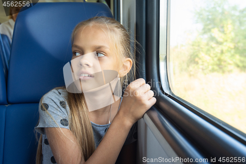 Image of Girl sitting by the window in an electric train car