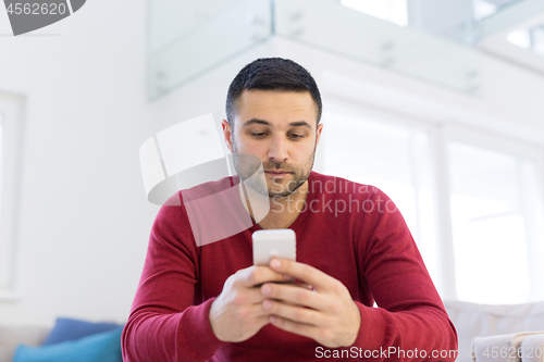 Image of young man using a mobile phone  at home