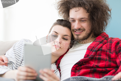 Image of couple relaxing at  home with tablet computers