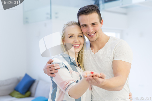 Image of couple showing small red house in hands