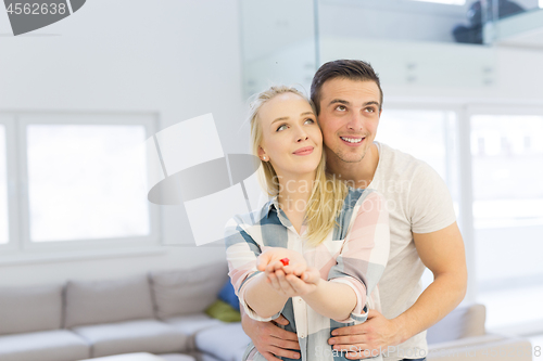 Image of couple showing small red house in hands