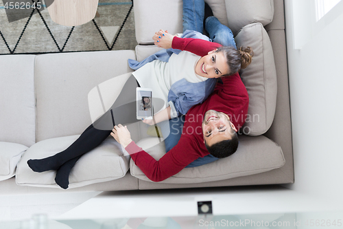 Image of couple relaxing at  home with tablet computers