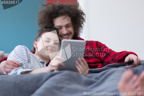 Image of couple relaxing at  home with tablet computers