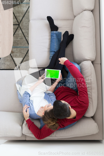 Image of couple relaxing at  home with tablet computers