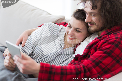 Image of couple relaxing at  home with tablet computers