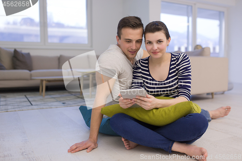 Image of Young Couple using digital tablet on the floor