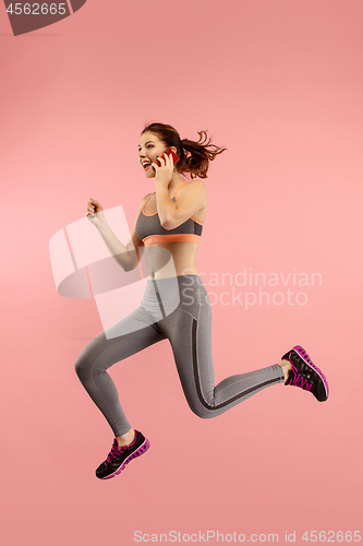 Image of Full length of pretty young woman with mobile phone while jumping