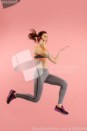 Image of Full length of pretty young woman with mobile phone while jumping