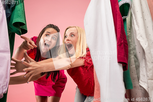 Image of The two young pretty girls looking at dresses and try on it while choosing at shop