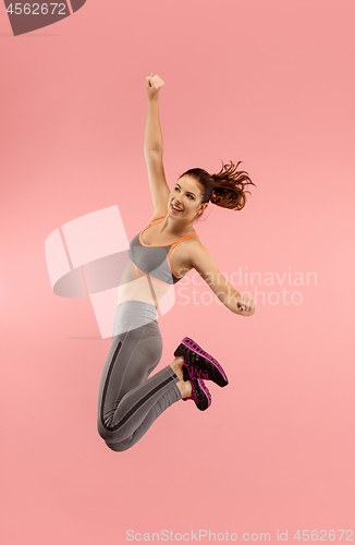 Image of Freedom in moving. Pretty young woman jumping against orange background