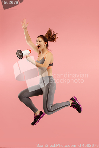 Image of Beautiful young woman jumping with megaphone isolated over red background