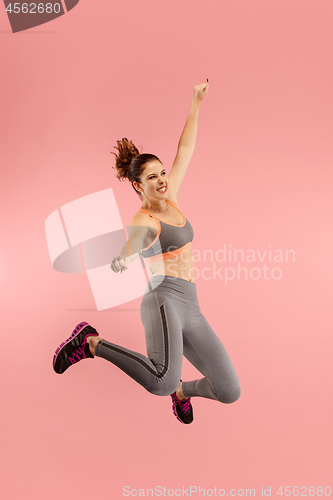 Image of Freedom in moving. Pretty young woman jumping against orange background