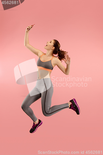 Image of Full length of pretty young woman with mobile phone while jumping