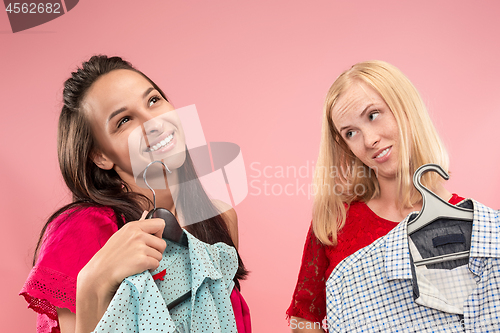 Image of The two young pretty girls looking at dresses and try on it while choosing at shop