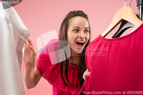 Image of The young pretty girl looking at dresses and try on it while choosing at shop