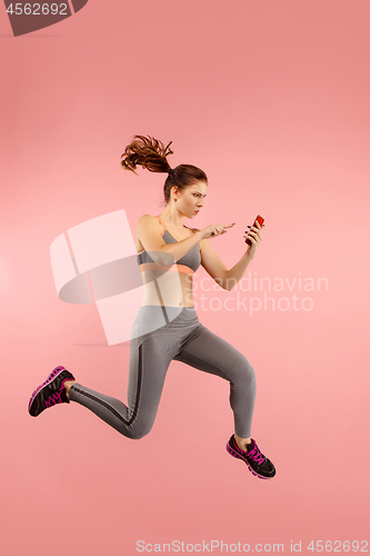 Image of Full length of pretty young woman with mobile phone while jumping