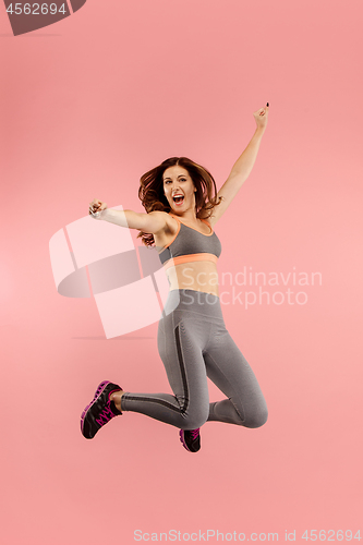 Image of Freedom in moving. Pretty young woman jumping against orange background