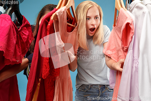 Image of The two young pretty girls looking at dresses and try on it while choosing at shop