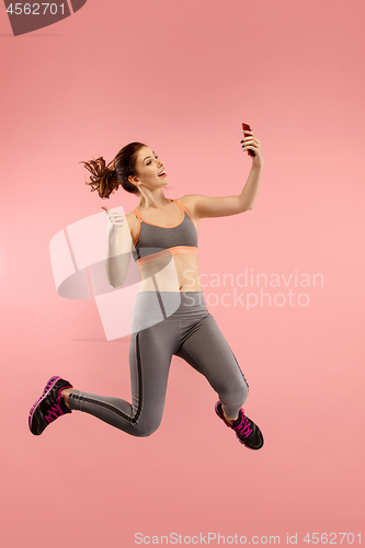 Image of Full length of pretty young woman with mobile phone while jumping