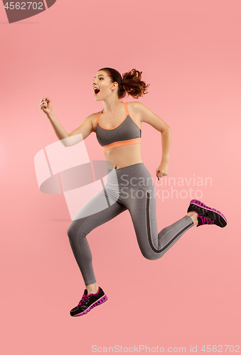 Image of Freedom in moving. Pretty young woman jumping against orange background