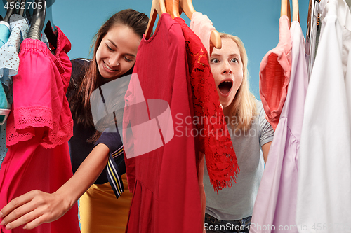 Image of The two young pretty girls looking at dresses and try on it while choosing at shop