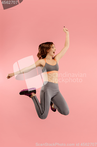 Image of Freedom in moving. Pretty young woman jumping against orange background