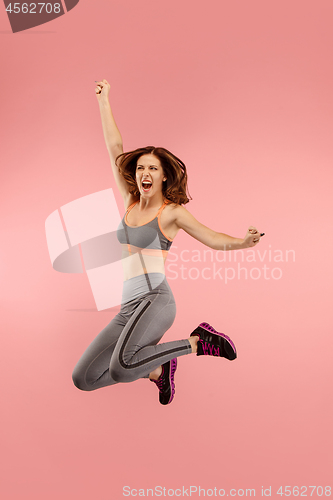 Image of Freedom in moving. Pretty young woman jumping against orange background