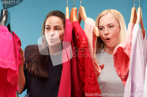 Image of The two young pretty girls looking at dresses and try on it while choosing at shop