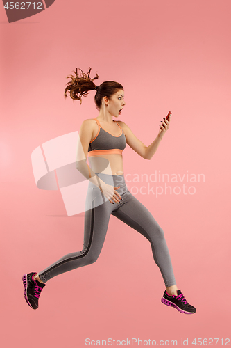 Image of Full length of pretty young woman with mobile phone while jumping