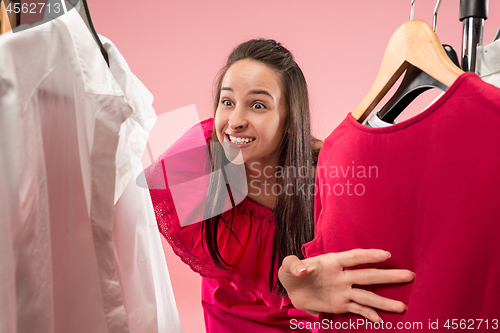 Image of The young pretty girl looking at dresses and try on it while choosing at shop