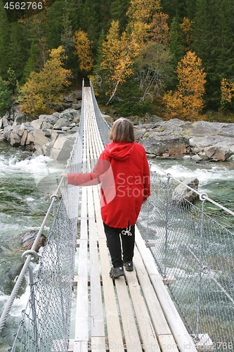 Image of Woman walking on a suspension bridge