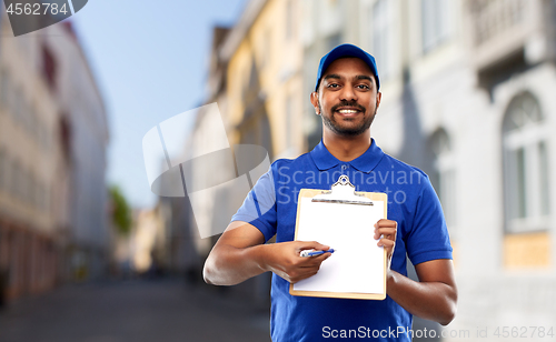 Image of happy indian delivery man with clipboard in city