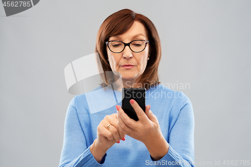 Image of senior woman in glasses using smartphone