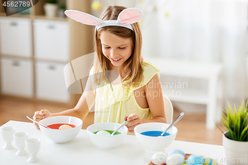 Image of girl coloring easter eggs by liquid dye at home