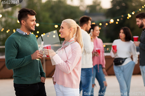 Image of friends with drinks in party cups at rooftop