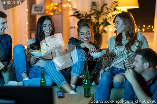 Image of friends with drinks and snacks watching tv at home