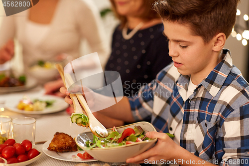 Image of close up of boy with salad at family dinner party