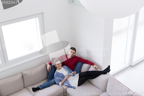 Image of couple relaxing at  home with tablet computers