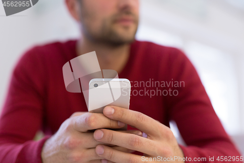 Image of young man using a mobile phone  at home