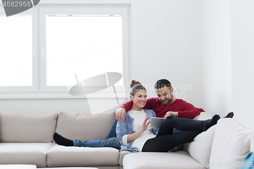 Image of couple relaxing at  home with tablet computers