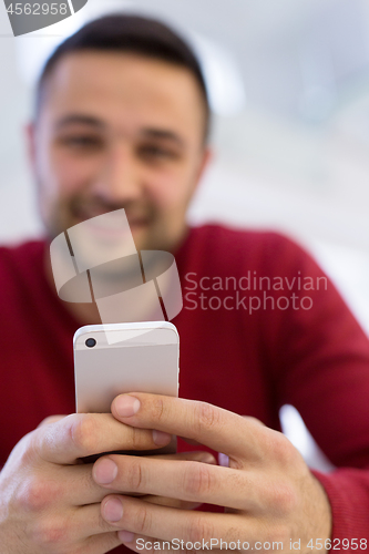 Image of young man using a mobile phone  at home