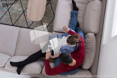 Image of couple relaxing at  home with tablet computers