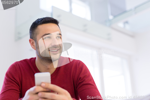 Image of young man using a mobile phone  at home