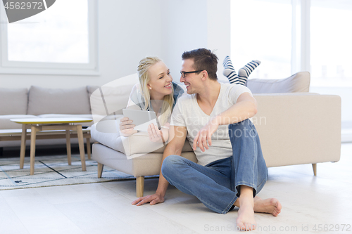 Image of couple relaxing at  home with tablet computers