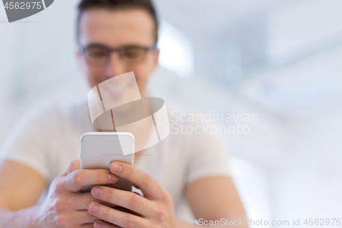 Image of young man using a mobile phone  at home