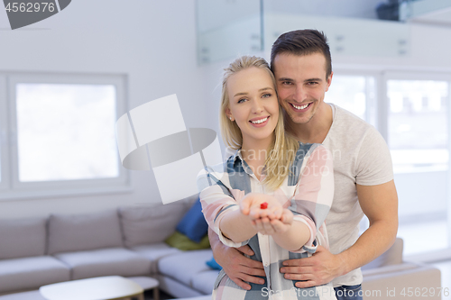 Image of couple showing small red house in hands