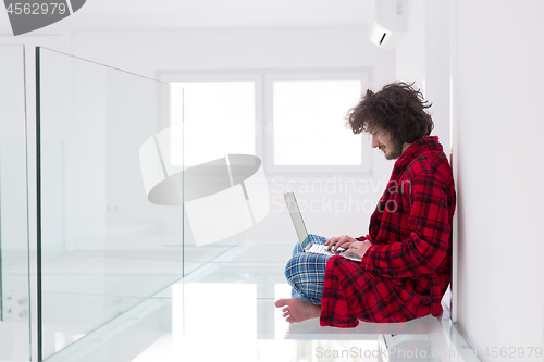 Image of young freelancer in bathrobe working from home